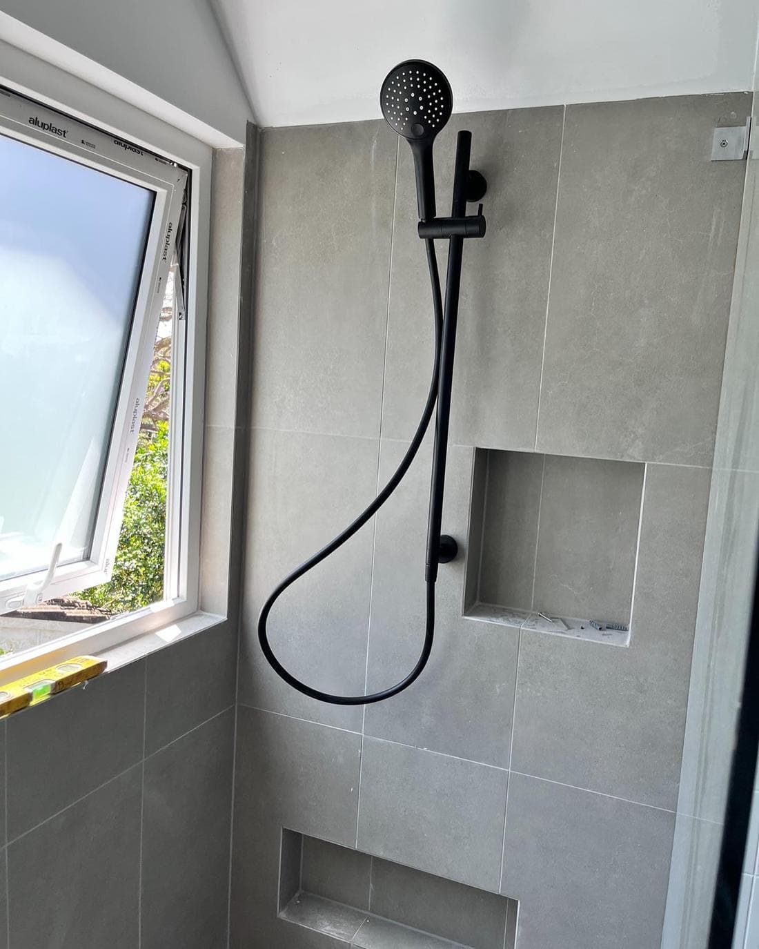 New black shower rail and rail set on grey tiled wall